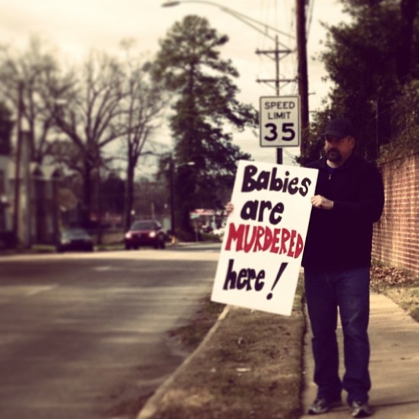 Mike Anderson holds a sign in front of Hope Medical Group, informing the public that babies are murdered there.